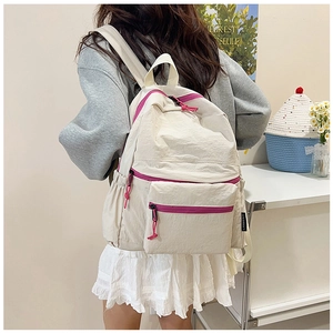 Detail of minimalist beige nylon backpack with rose red zippers and pink decorative cords