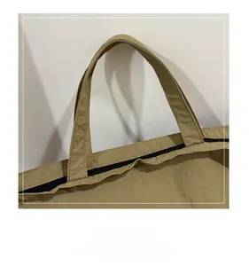 Close-up of khaki canvas tote bag featuring reinforced stitching and black zipper closure