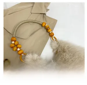 Détail de la poignée en perles et de la fourrure synthétique du sac à main beige