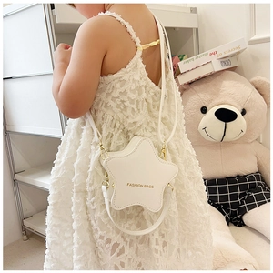 Close-up of a white star-shaped mini shoulder bag worn by a young girl in a cozy room