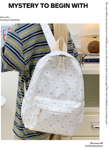 Detail of white backpack with blue heart prints featuring rope zipper and side pocket