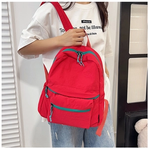 Detail view of the red casual backpack showing multiple zippered pockets and blue pull cords
