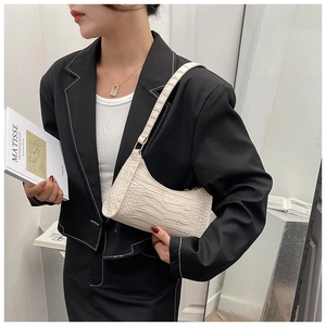 Detail view of the cream crocodile pattern hobo bag worn with a black suit blazer