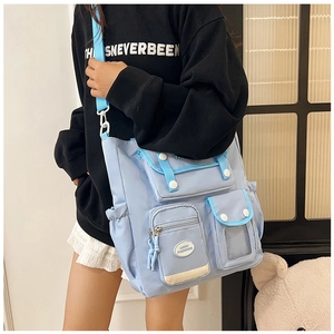 Detail of light blue nylon crossbody bag with multiple pockets and white strap accents
