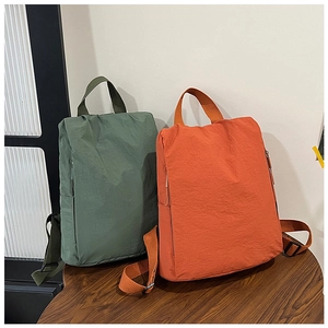 Army green and orange nylon backpacks with wrinkled texture on wooden table