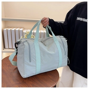 Detail of mint green nylon travel bag showing waterproof fabric and shoulder strap hooks