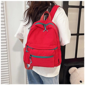Detail of red travel backpack with wear-resistant fabric and blue drawstring zipper pulls