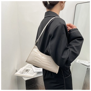 Close-up of cream white crocodile embossed hobo bag worn over the shoulder in a minimalist setting