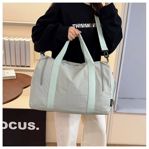 Detail view of large nylon travel bag with mint green straps and side zipper pocket