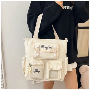 Detailed view of a cream white canvas tote bag with functional pockets and embroidery