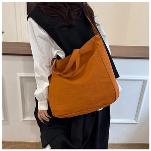 Back view of a large orange canvas tote bag worn by a model for a casual commute look