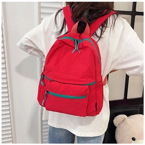 Detailed view of casual red backpack featuring vibrant green zippers and multiple pockets