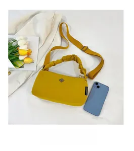 Detail of yellow nylon crossbody bag with silver flower logo and adjustable wide strap