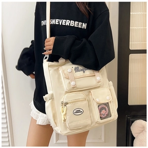 Detail of a creamy white multi-pocket canvas crossbody bag with adjustable strap