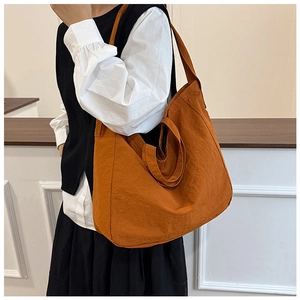 Detail of caramel orange nylon tote bag showing double handles and crinkled texture