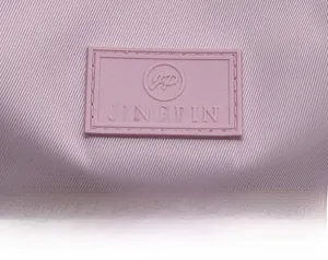 Close-up of a purple nylon backpack showing the JINGPIN embossed logo and twill texture