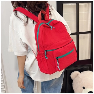 Detailed view of red nylon backpack with vibrant blue zipper contrast on female model