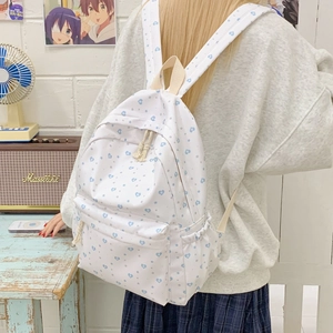 Detail of white canvas backpack with blue heart patterns and padded shoulder straps