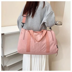 Detail showing the side zipper pocket and adjustable strap of a pink nylon travel bag