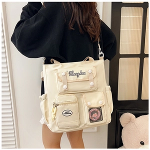 Detail of off-white large capacity tote bag featuring multi-pocket design and badges