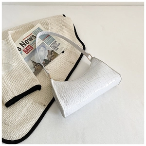 Close-up of white baguette bag featuring crocodile pattern leather and metallic ring hardware
