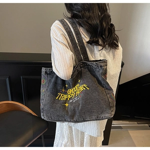 Détail du sac cabas en toile délavée avec broderie étoile colorée et texte artistique