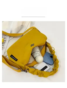 Spacious interior of yellow nylon shoulder bag showing room for umbrella and smartphone