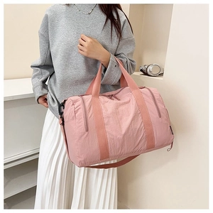 Close-up of pink nylon travel bag featuring textured fabric and adjustable shoulder strap