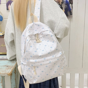 Detail of white canvas backpack featuring blue heart and gray star patterns for students