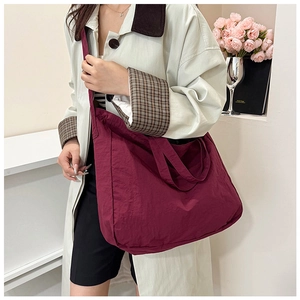 Detail of burgundy large capacity tote bag with wrinkled texture and wide shoulder strap