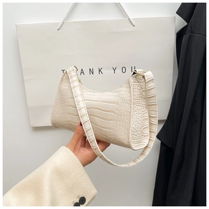 Detail view of cream faux crocodile texture on a minimalist crescent underarm bag