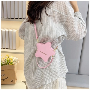 Detail of pink star-shaped crossbody bag with gold zipper on a feminine lace outfit