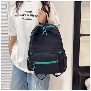 Close-up of black nylon backpack with mint green zipper details worn by a model