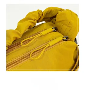 Detailed close-up of smooth double zippers and pleat handle on ginger yellow nylon bag