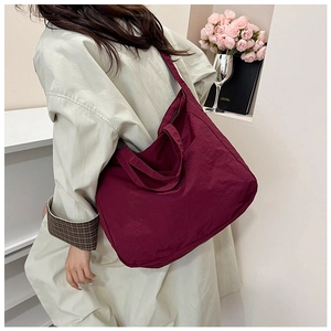 Detail of burgundy canvas tote bag with wrinkled texture and wide shoulder strap