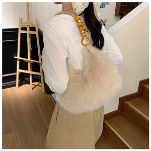 Détail du sac sous le bras en peluche crème avec de grandes perles orange sur la bandoulière