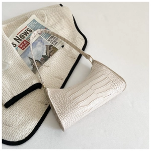 Close-up of off-white faux crocodile pattern underarm bag with gold metal buckle