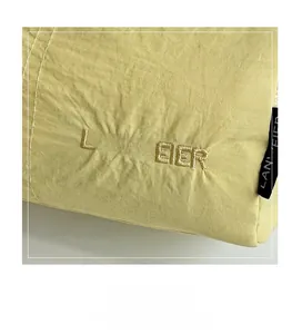 Close-up of yellow nylon square bag featuring Lanweier embroidery and pleated texture