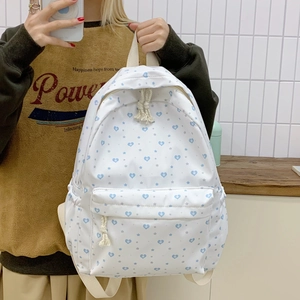 Detail of white backpack featuring blue heart and star patterns with front zip pocket