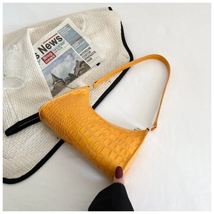Close-up of bright yellow hobo bag with crocodile embossed texture and metal hardware