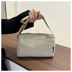 Close-up of beige nylon crossbody bag with LANWEIER embroidery on textured fabric