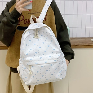 Detailed close-up of a white backpack with heart and star patterns and knotted zipper pulls