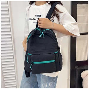 Detail of black casual backpack with contrasting teal zippers and smooth nylon texture