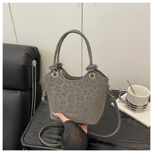Close-up of leopard print gray suede bucket bag with gold hardware and stylish wave edge