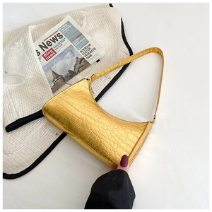 Detail of golden crocodile embossed leather bag with glossy metallic finish and slim strap