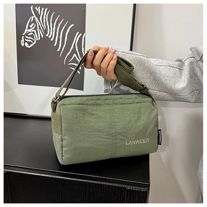 Detailed embroidery logo on a green nylon crossbody bag with wide shoulder strap