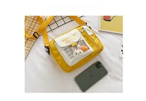 Détail du sac à bandoulière en toile jaune avec rabat blanc et texte HELLO Girl imprimé