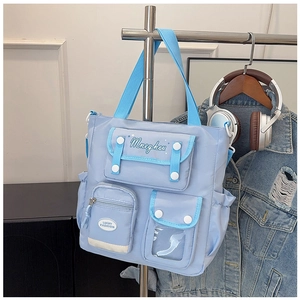 Close-up of light blue nylon tote bag showing multiple pockets and transparent insert window