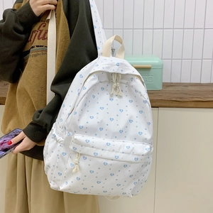 Close-up of white canvas backpack with blue heart prints and woven rope zipper details