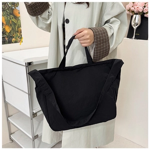 Detail showing the large black canvas tote bag in a casual lifestyle setting for commute